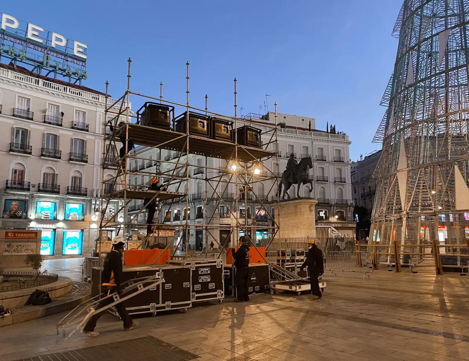 Montaje de estructura metálica en plaza central al atardecer.