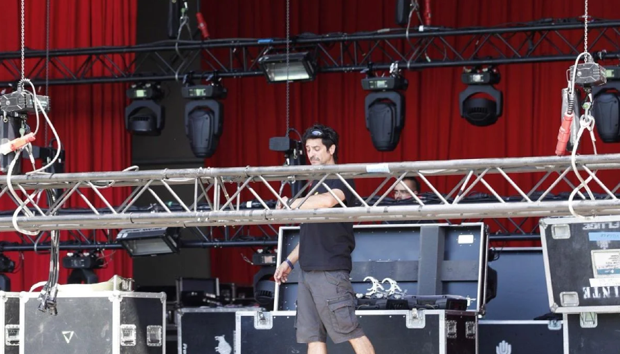 Técnico montando escenario con focos y equipo.