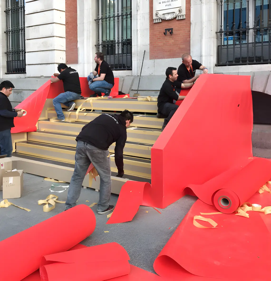 quienes somos 4 Personas montando estructura con papel rojo.