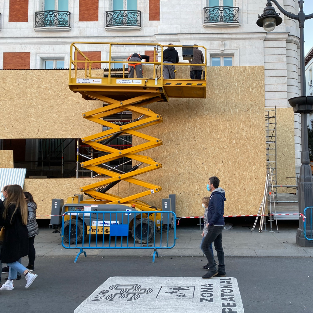 Obra en construcción con plataforma elevadora en la calle.