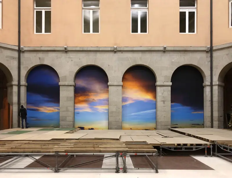 Escena de puesta de sol tras arcos de edificio.