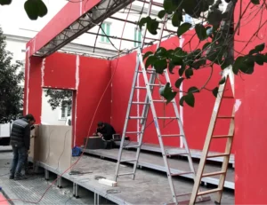 Construcción de escenario con paneles rojos y escaleras.